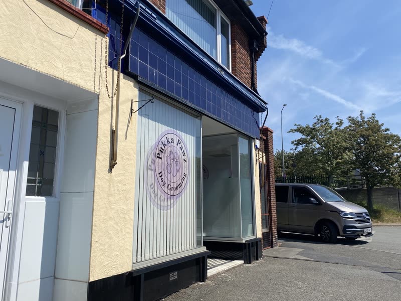 The Pukka Paws shopfront on Conway Road, a cream and navy terraced unit with a large plate-glass window, on a sunny day
